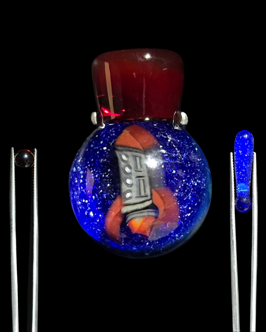 Glass pendant with a spaceship design inside a blue glittery sphere on a black background
